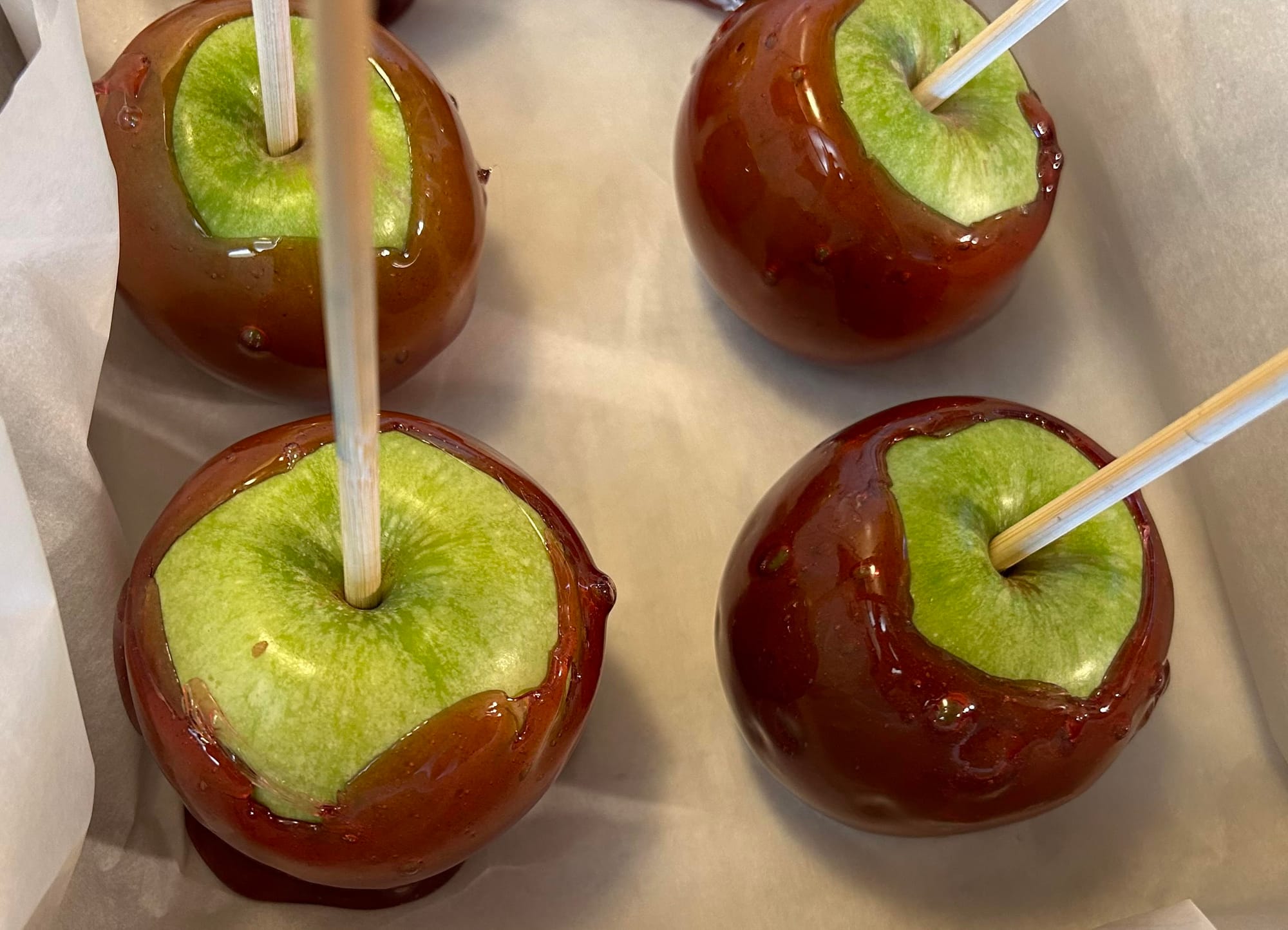 four candy apples, with purple candy over green granny smith apples